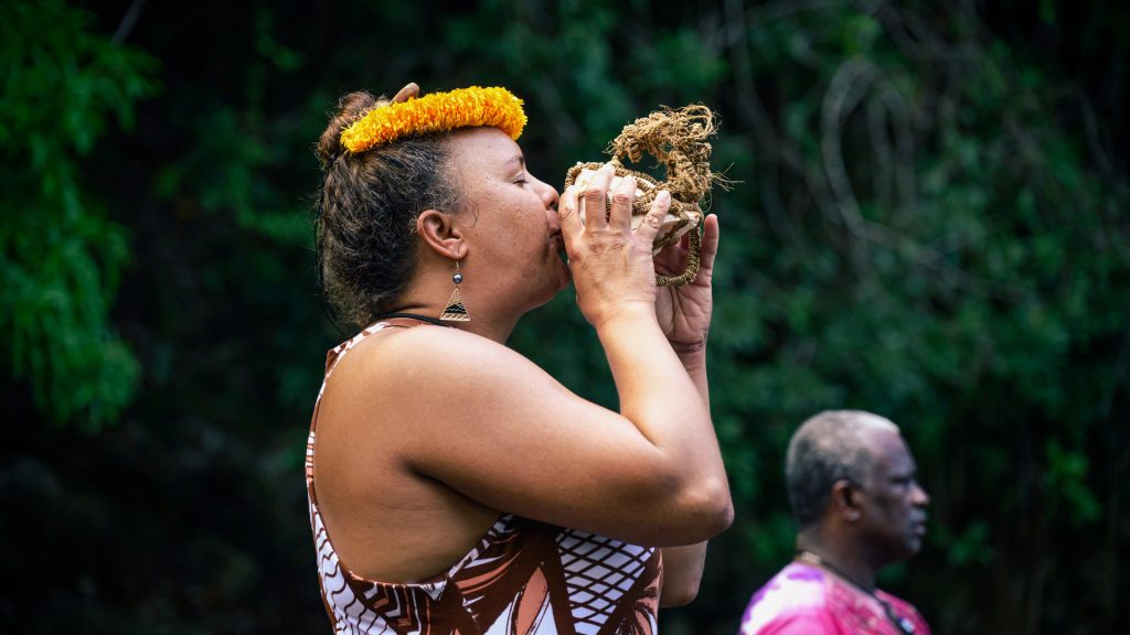 Dr-Britney-Lehua-Kamai-blows-conch-shell-in-the-Asafu-Yard-at-Charles-Town-Maroon-Village-Jamaica-
